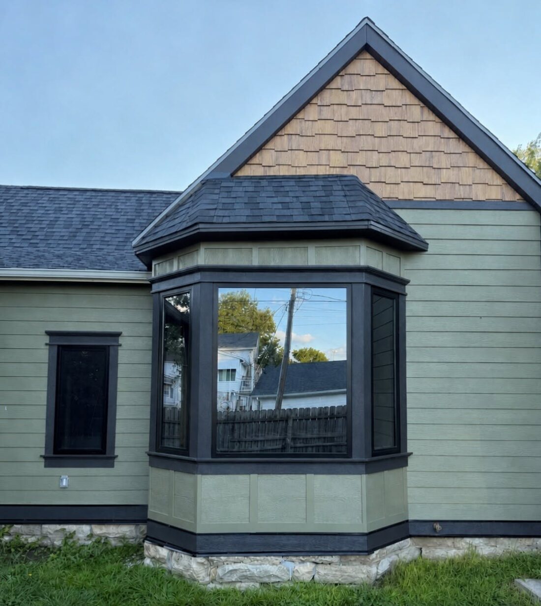 Installed black-framed bay window on a finished exterior